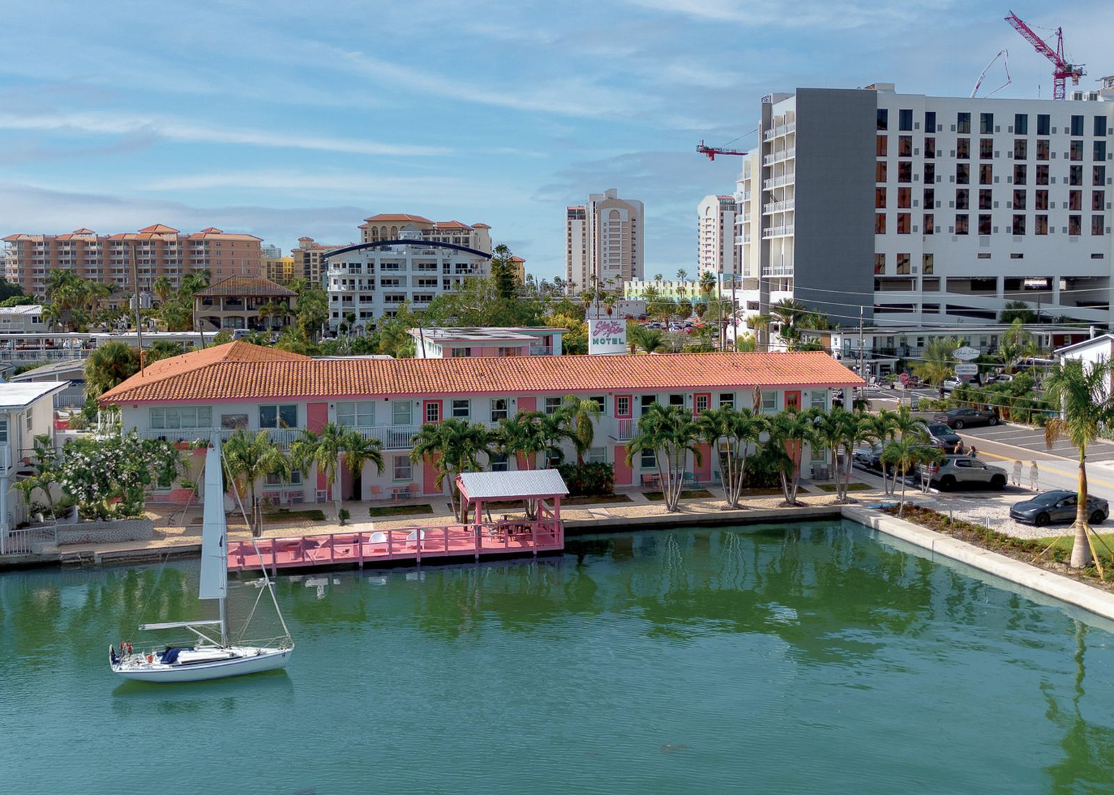 Pink-doored motel building on the water in Clearwater Beach, with a sailboat moored at the dock